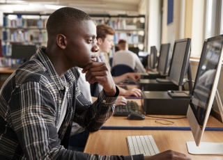 A high school student works at a computer in his school library 